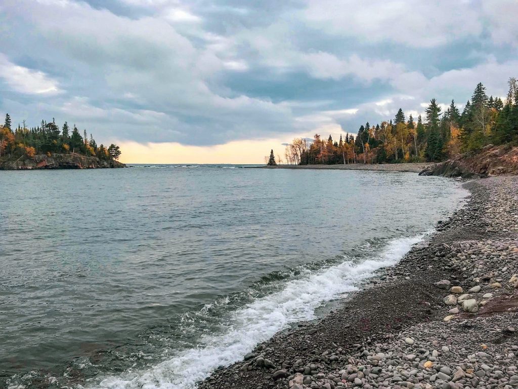 Lake Superior shoreline in autumn with colourful trees and clouds overhead. 