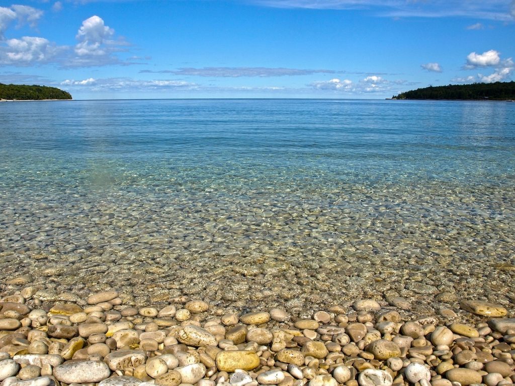 Rivage du lac Michigan avec de nombreux rochers le long de la rive et des forêts à l'horizon. 